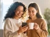 Zwei Frauen schauen gemeinsam auf ein Smartphone und lächeln