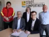 Carsten Hoffmann und Marius Schmidt beim Unterzeichnen des Vertrags. Dahinter: Felix Kröger und Susanne Hanselmann vom Vorstand der DLRG Lampertheim und Rainer Babylon von der GGEW.