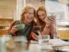 Seniorin und junge Frau schauen lächelnd auf ein Smartphone