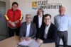 Carsten Hoffmann und Marius Schmidt beim Unterzeichnen des Vertrags. Dahinter: Felix Kröger und Susanne Hanselmann vom Vorstand der DLRG Lampertheim und Rainer Babylon von der GGEW.