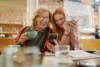 Seniorin und junge Frau schauen lächelnd auf ein Smartphone