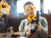 Eine Tischlerin zieht sich ihre Arbeitshandschuhe an