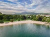 Türkiser See mit Strand und grüner Wiese dahinter